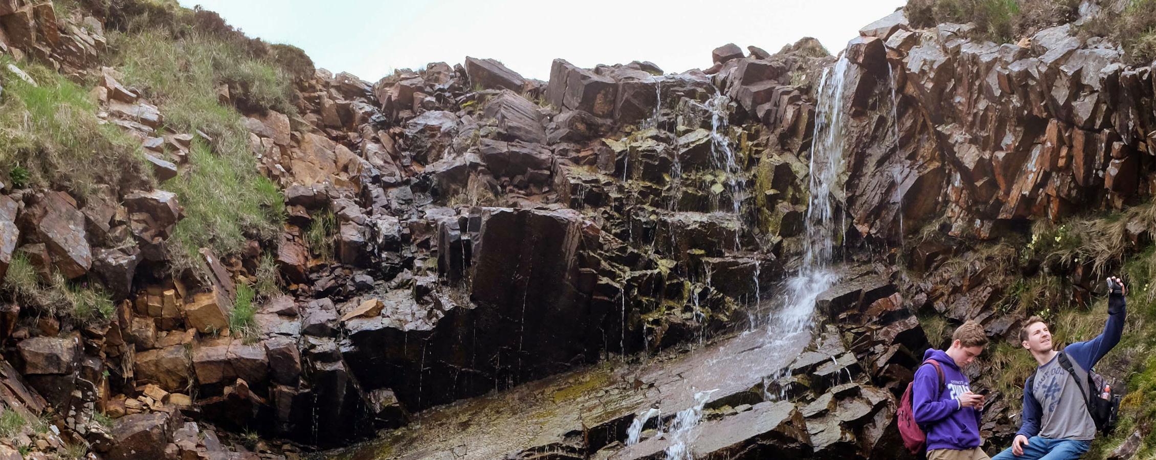 Students from 足彩平台 visit a waterfall during a travel study.