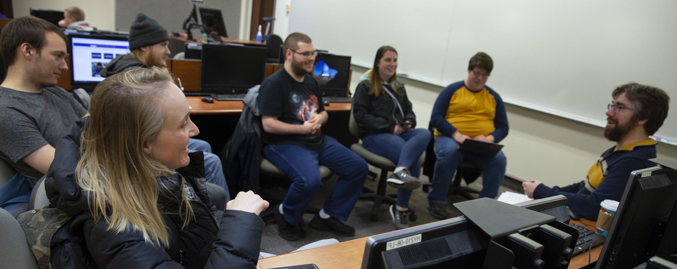 Students gather with a faculty member at a table.