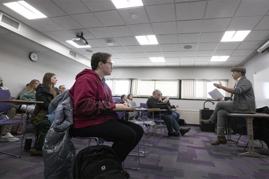 Nick Gulig sits on a table in front of class.