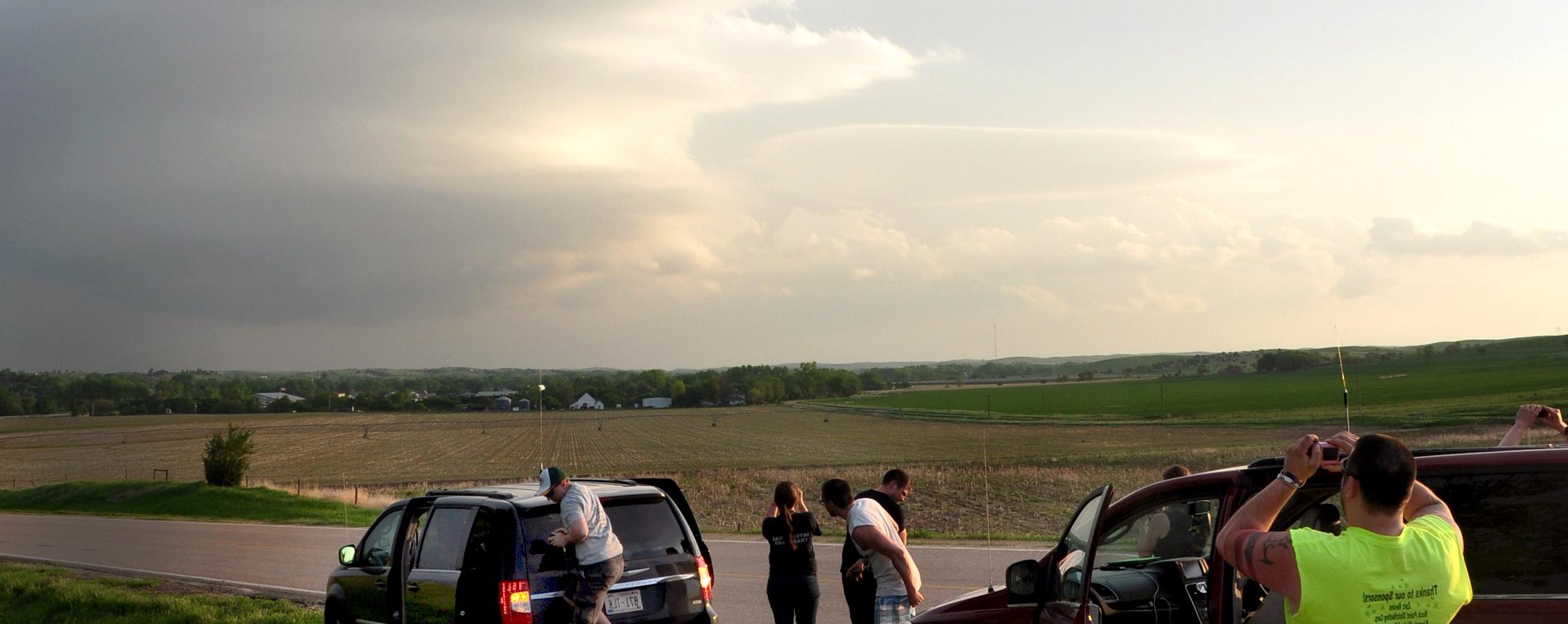 Students photograph a storm rolling in over a field.