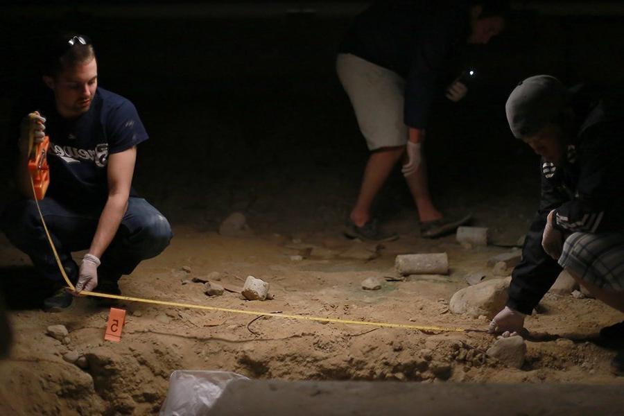 Two students use a tape measure at a mock crime scene.