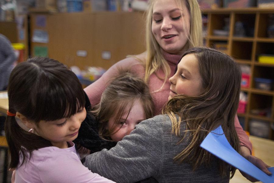 Hollyn Peterson hugs young students.